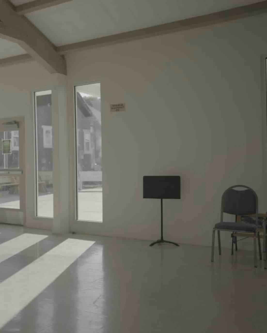 A lone chair sits next to a music stand in the annex of a church.