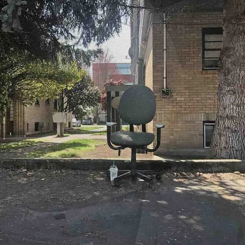 A rolling office chair abandoned behind a building.
